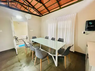 a dining room with a glass table and chairs at The Hive at Druv Dakshin Farm Resort in Padinjarathara
