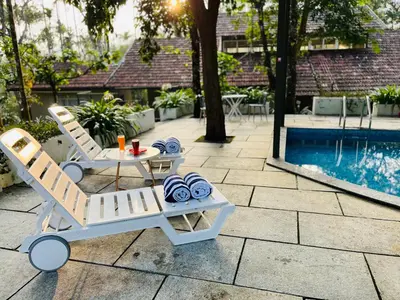 a pair of chairs and a table next to a pool at The Hive at Druv Dakshin Farm Resort in Padinjarathara