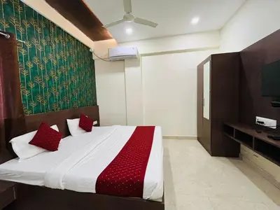 a bedroom with a bed with red pillows and a tv at My Rooms Channapatna in Channapatna