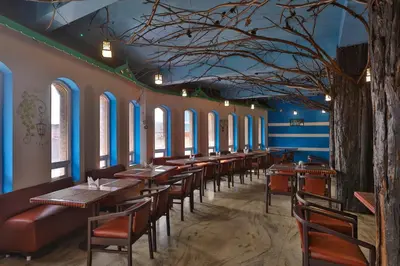 a dining room with tables and chairs and a tree at Devi Enterprises - Hotel Khems in Ooty