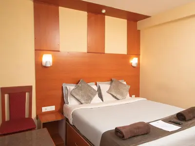 a bedroom with a bed and a desk with a chair at Devi Enterprises - Hotel Khems in Ooty