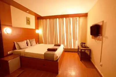 a small bedroom with a bed and a television at Devi Enterprises - Hotel Khems in Ooty