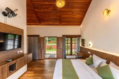 a bedroom with a bed and a flat screen tv at Theyila Wayanad Premium Pool Resort in Sultan Bathery