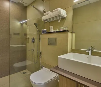 a bathroom with a toilet and a sink and a shower at Grand Continent Mysore A Sarovar Portico Affiliate Hotel in Mysore