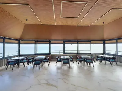 a dining room with tables and chairs and windows at The Cabana in Cherai Beach
