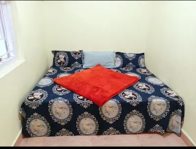 a bed with a red blanket on top of it at Valley homes in Ooty