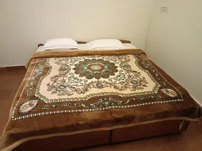 a bed with a blanket on top of it at Abbu Royal Palace Cottage in Ooty