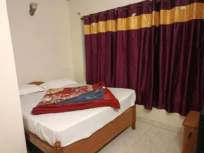 a bedroom with a bed with a red curtain at Abbu Royal Palace Cottage in Ooty