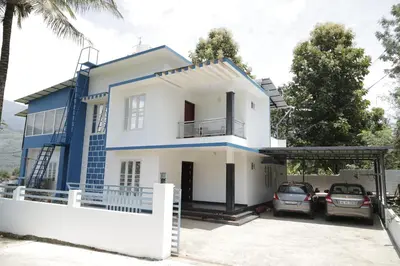 a house with two cars parked in front of it at Le Sancta homestay in Marayoor