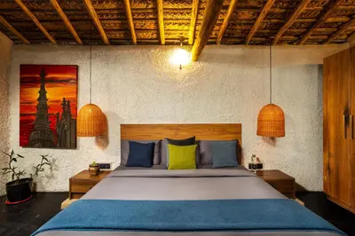 a bedroom with a large bed with blue and yellow pillows at Kudisai Marayoor - Munnar in Munnar