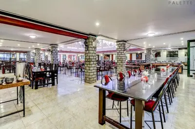 a dining room with tables and chairs in a restaurant at Heritage Shelters Resort in Mysore