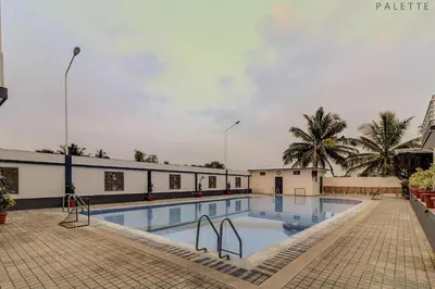 a large swimming pool in a building with palm trees at Heritage Shelters Resort in Mysore