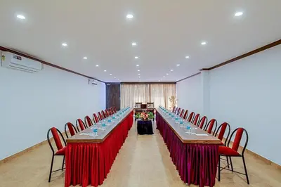 a conference room with long tables and red chairs at Heritage Shelters Resort in Mysore
