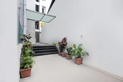 a corridor of a white building with potted plants at Super Townhouse City Center Near Mysore Palace Formerly Aavass Inn in Mysore