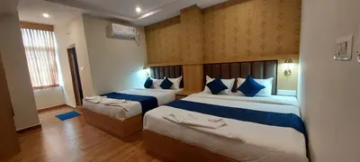 a hotel room with two beds with blue pillows at Sky Inn in Mysore