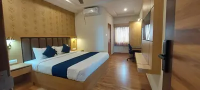 a hotel room with a bed and a desk and a room at Sky Inn in Mysore