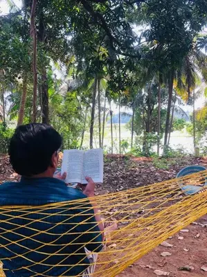 a man sitting on a bench reading a book at Neermathalam, a traditional kerala tharavadu in Palakkad