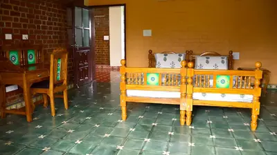 a room with two wooden beds and a table at Lakshmi illam Near Isha Yoga Adiyogi in Alāndurai