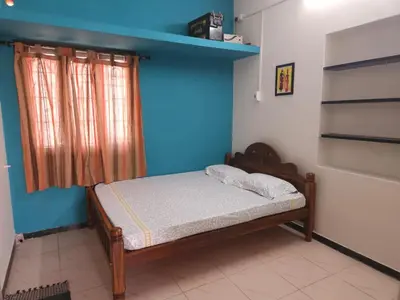 a bedroom with a bed and a blue wall at SHIs Spandha Apartments Near Coimbatore Airport in Coimbatore