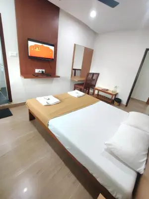 a bedroom with a large bed with a tv on the wall at Nandan Residency in Mysore