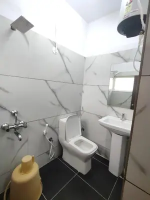 a white bathroom with a toilet and a sink at Nandan Residency in Mysore