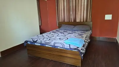 a bedroom with a bed with a wooden headboard at Golden Nest Home Stay in Mysore