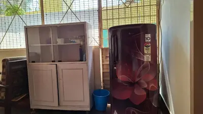 a refrigerator and a cabinet in a room at Golden Nest Home Stay in Mysore