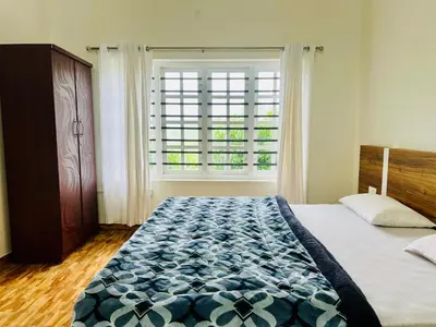 a bedroom with a bed and a window at Teyt's Green Haven - 3 BHK in Ooty
