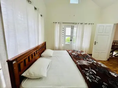 a bedroom with a large bed with a wooden headboard at Teyt's Green Haven - 3 BHK in Ooty
