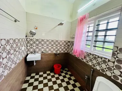 a bathroom with a sink and a red trash can at Teyt's Green Haven - 3 BHK in Ooty