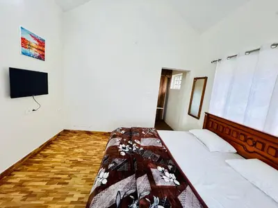 a bedroom with a bed and a flat screen tv at Teyt's Green Haven - 3 BHK in Ooty