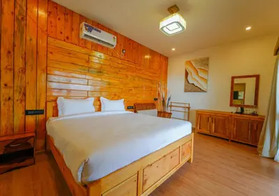 a bedroom with a bed with a wooden wall at Silent Retreat Ooty Pool Resort by VOYE HOMES in Ooty