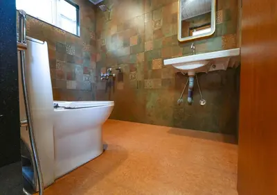 a bathroom with a toilet and a sink at Silent Retreat Ooty Pool Resort by VOYE HOMES in Ooty