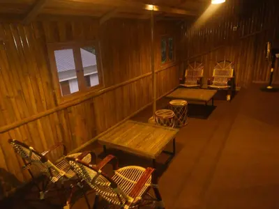 an empty room with benches and chairs in a cabin at Bamboo Suite at Merlys Fruit Garden in Kotamangalam
