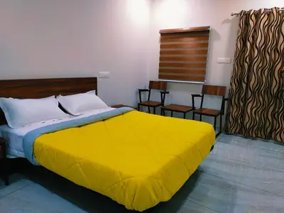 a bedroom with a large yellow bed and chairs at Bamboo Suite at Merlys Fruit Garden in Kotamangalam