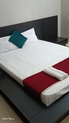a large white bed with a green pillow on it at Midtown Residency in Kozhikode