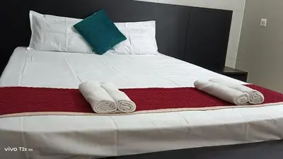 a bed with three towels on a red and white blanket at Midtown Residency in Kozhikode