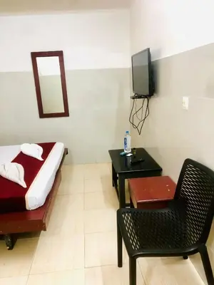 a room with a bed and a chair and a television at Midtown Residency in Kozhikode