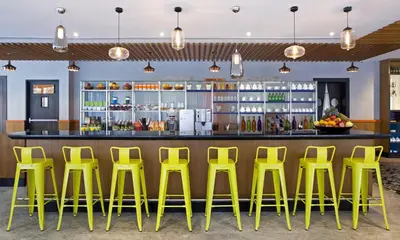 a bar with yellow stools in front of a counter at Zone By The Park Coimbatore in Coimbatore