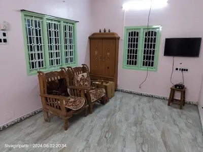 a living room with chairs and a flat screen tv at Honeycomb Homestay Ground Floor in Palani
