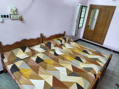 a bedroom with a bed with a colorful quilt at Honeycomb Homestay Ground Floor in Palani