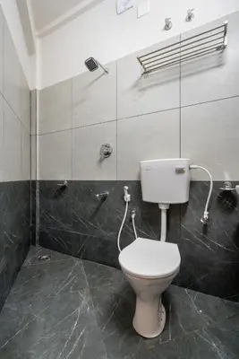 a bathroom with a white toilet in a room at Amala Arcade AC Rooms in Trichūr