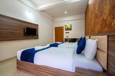 a hotel room with two beds and a television at Amala Arcade AC Rooms in Trichūr