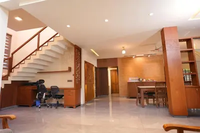 a living room with a staircase and a table and chairs at Sannidhi Homes Palakkad in Palakkad