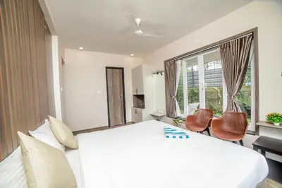 a bedroom with a large white bed and chairs at Abhinav Nest by Xplore Indo in Kodanād