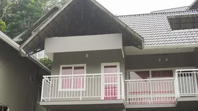 a house with a balcony with pink doors at Rains Valley Resort By Teal Luxury Stays in Viripara