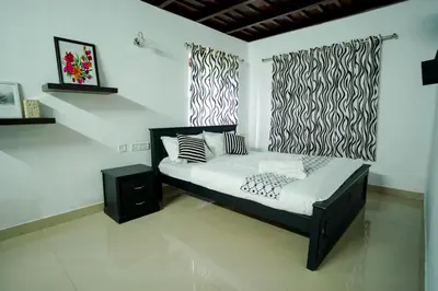a bedroom with a bed with black and white pillows at Wayanad Palm Grove Retreat 1st Floor in Wayanad