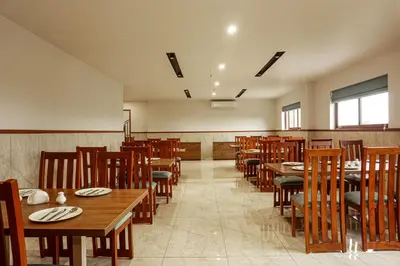 a dining room with wooden tables and chairs at Sahya Regency in Ottappālam