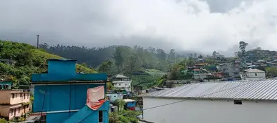 a city with a blue building and a mountain at Swarna Tourist home Munnar in Munnar