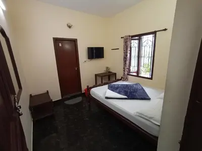 a small bedroom with a bed and a window at Swarna Tourist home Munnar in Munnar